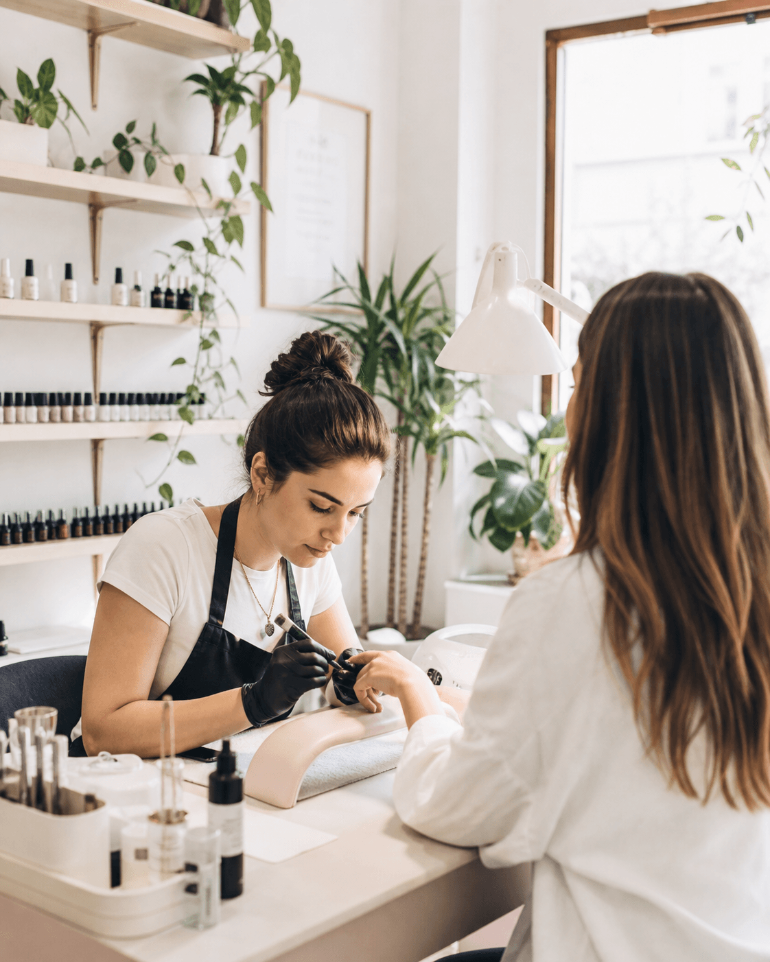 Esteticista atendiendo a una clienta en un estudio de uñas luminoso
